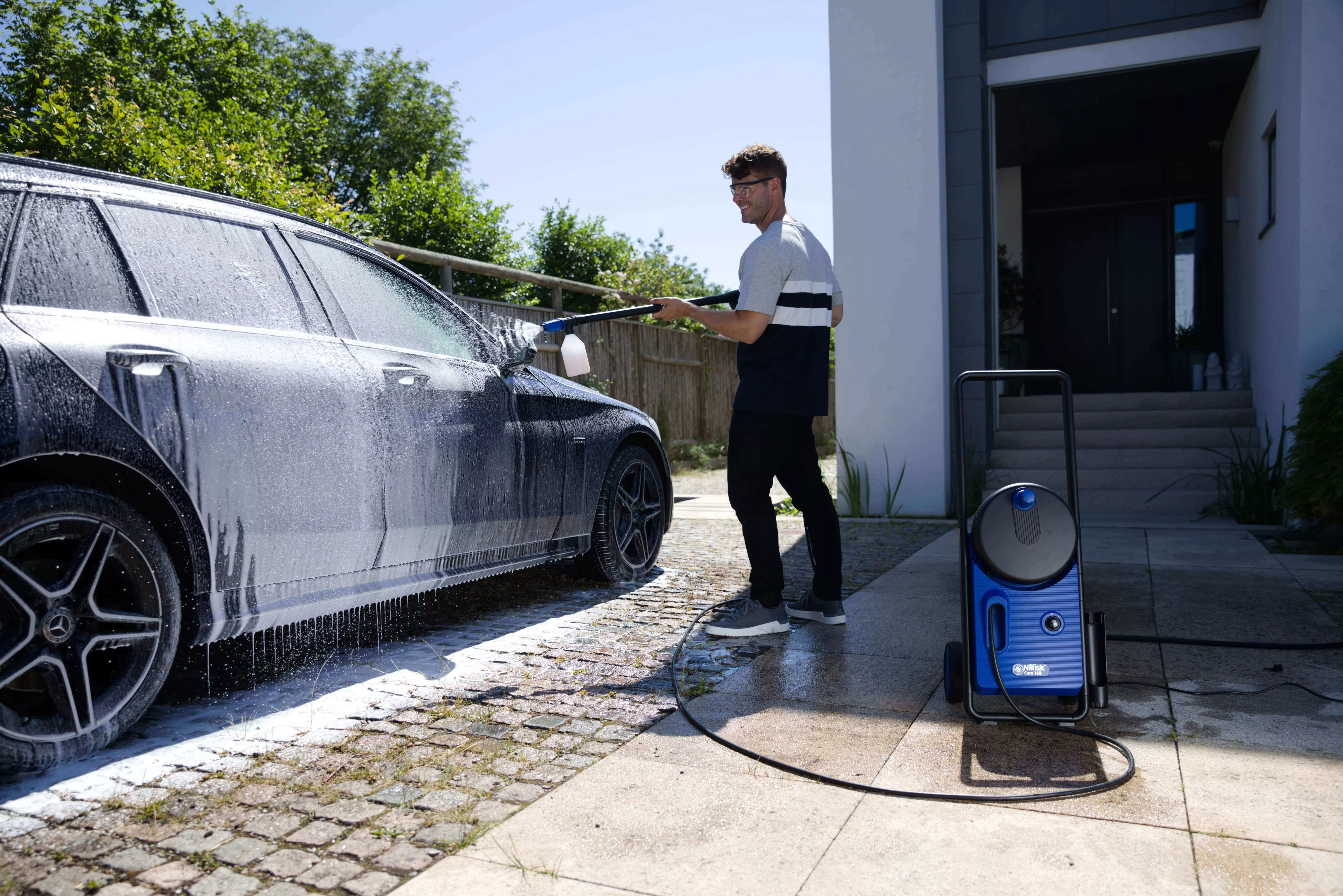 Man cleaning car with high pressure washer and super foam sprayer detergent