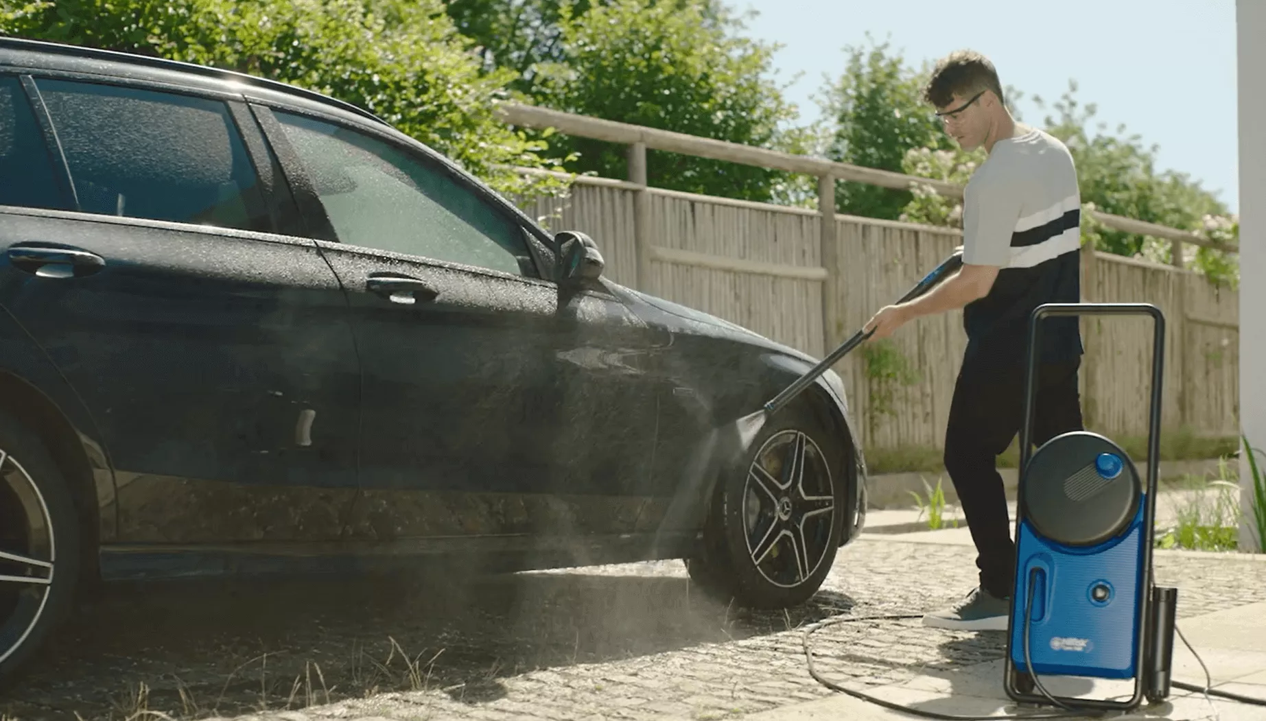 Man cleaning wheel on car with high pressure washer